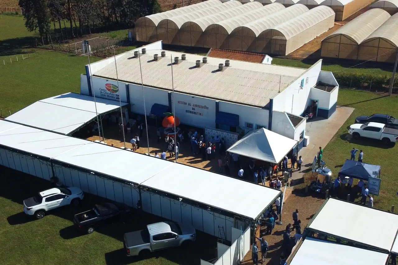 Vista aérea do Centro de Convenções da Citricultura, no Centro de Citricultura Sylvio Moreira, com tendas e público na área externa e estufas ao fundo